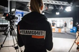 Mitarbeiterin Denise von GO4IT im GO4IT Hoodie schaut auf Dreh im Studio4.DIGITAL