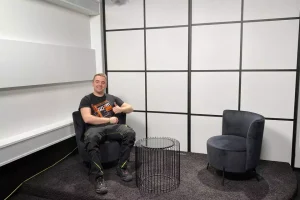 Mitarbeiter von GO4IT sitzt auf Sessel im Studio und zeigt Daumen hoch